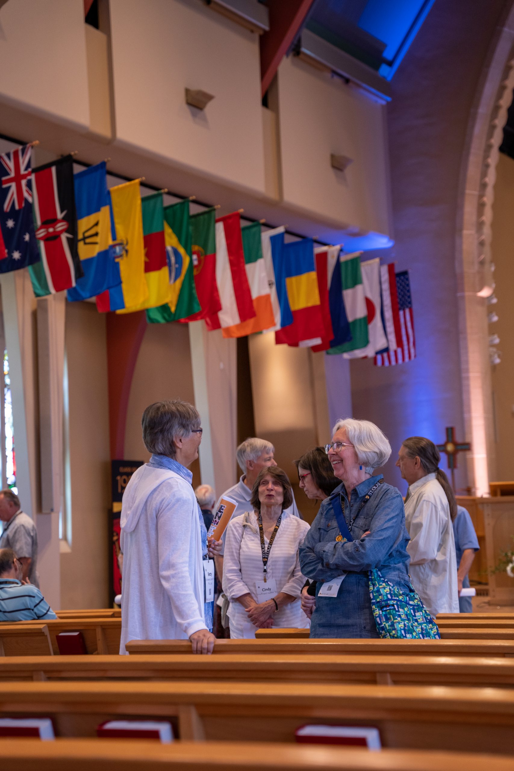 People standing between pews under flags from various countries