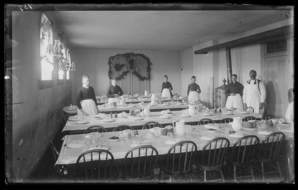 Old Main dining room with set tables and several staff members