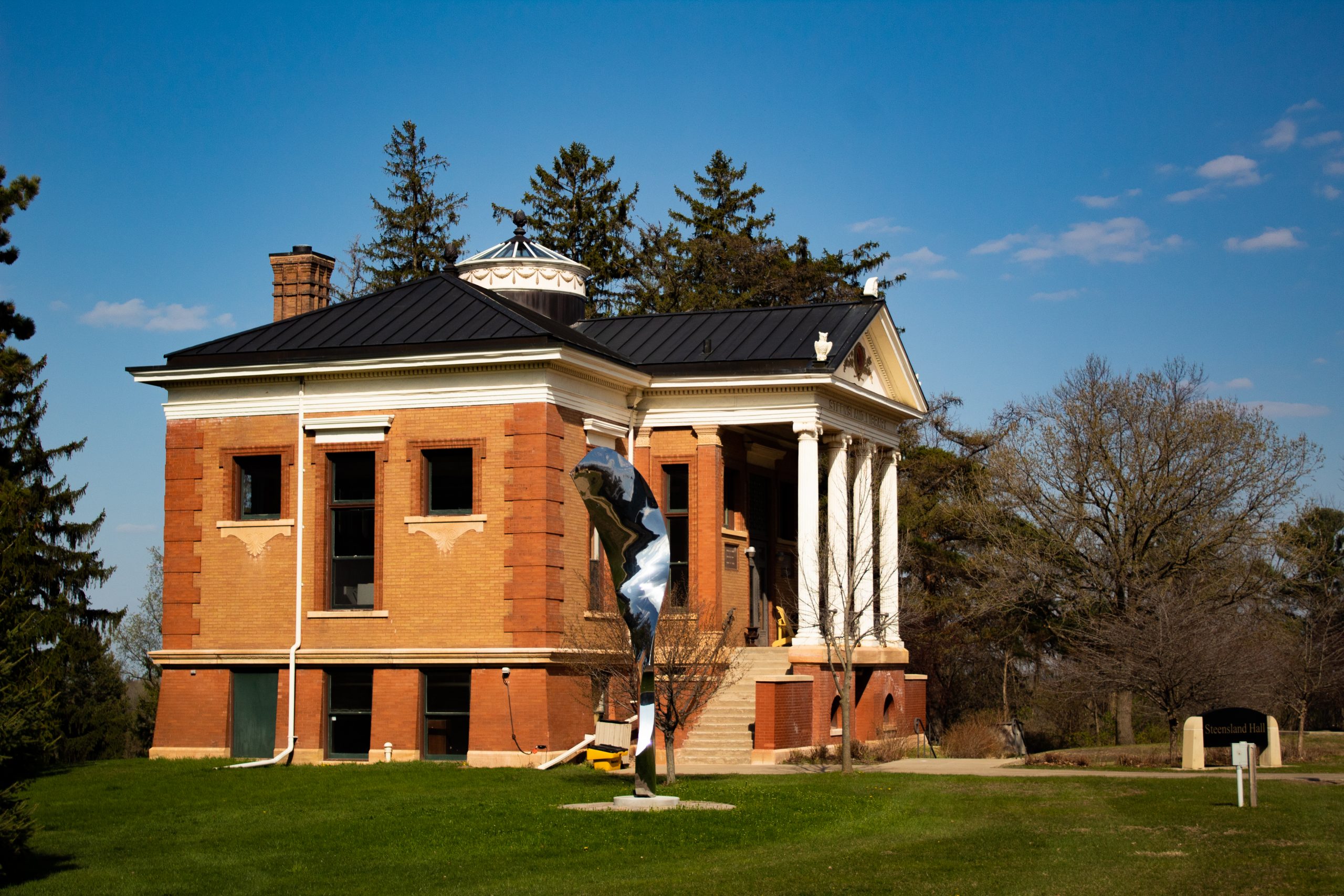 Steensland Hall with a shiny sculpture next to it